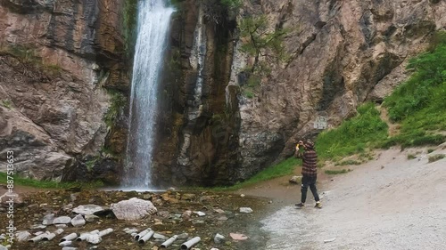 Tourist Photographs a Waterfall in the Mountains photo