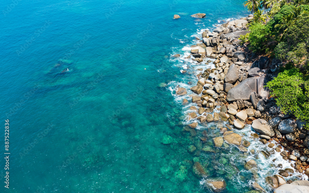 Aerial view of a rocky cliff and tree with turquoise ocean water. Aerial view of a rocky cliff and tree with turquoise ocean water.