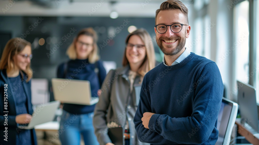 A group of cheerful young professionals in an office, smiling and holding laptops. A group of cheerful young professionals in an office, smiling and holding laptops.