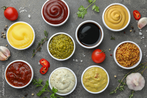 Many different sauces and spices on grey table, flat lay