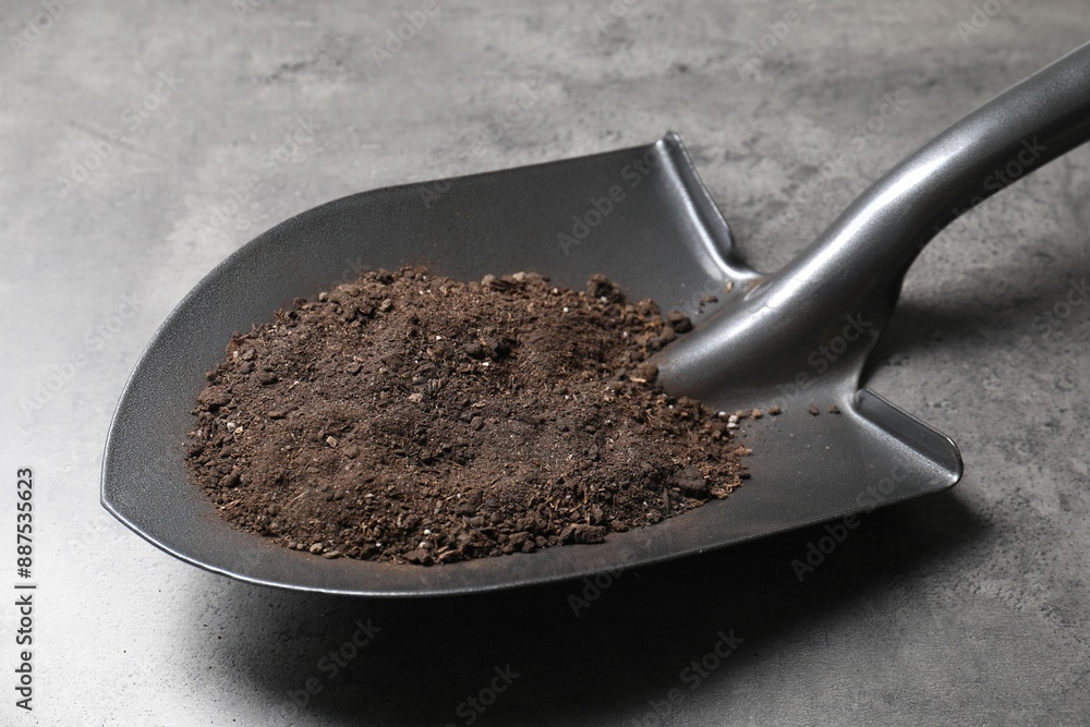 Metal shovel with soil on grey table, closeup Metal shovel with soil on grey table, closeup