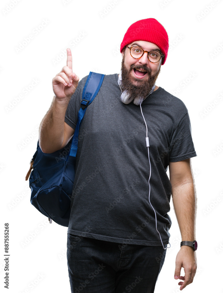 Naklejka premium Young hipster man wearing red wool cap and backpack over isolated background pointing finger up with successful idea. Exited and happy. Number one.