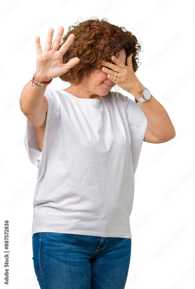 Beautiful middle ager senior woman wearing white t-shirt over isolated background covering eyes with hands and doing stop gesture with sad and fear expression. Embarrassed and negative concept. Beautiful middle ager senior woman wearing white t-shirt over isolated background covering eyes with hands and doing stop gesture with sad and fear expression. Embarrassed and negative concept.