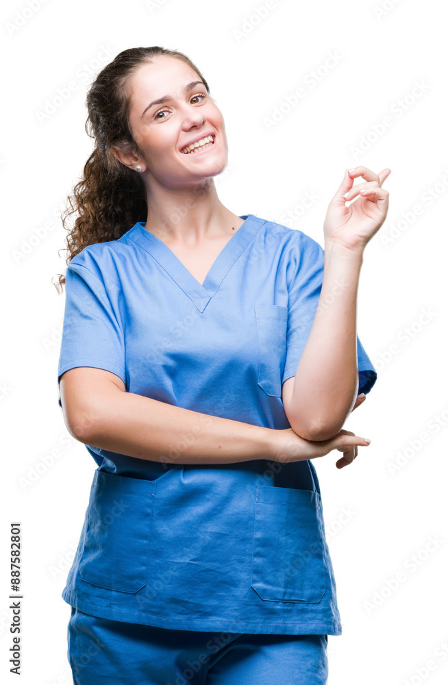 Young brunette doctor girl wearing nurse or surgeon uniform over isolated background with a big smile on face, pointing with hand and finger to the side looking at the camera. Young brunette doctor girl wearing nurse or surgeon uniform over isolated background with a big smile on face, pointing with hand and finger to the side looking at the camera.