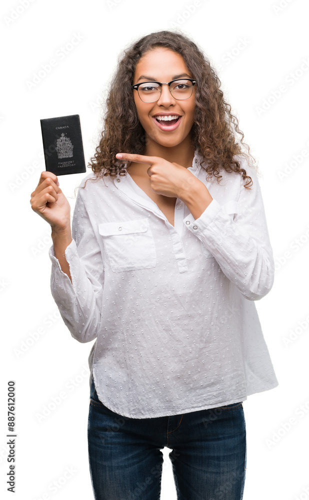 Young hispanic woman holding passport of Canada very happy pointing with hand and finger Young hispanic woman holding passport of Canada very happy pointing with hand and finger