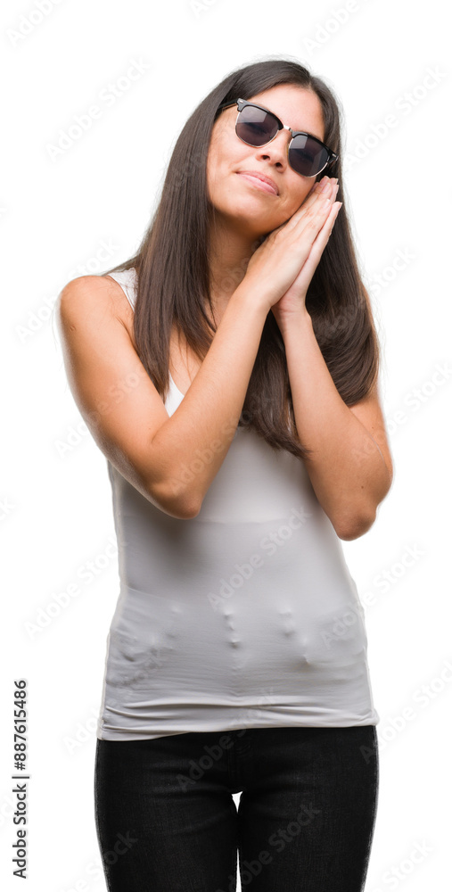 Obraz premium Young beautiful hispanic wearing sunglasses sleeping tired dreaming and posing with hands together while smiling with closed eyes.