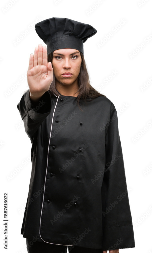 Young hispanic cook woman wearing chef uniform with open hand doing stop sign with serious and confident expression, defense gesture Young hispanic cook woman wearing chef uniform with open hand doing stop sign with serious and confident expression, defense gesture