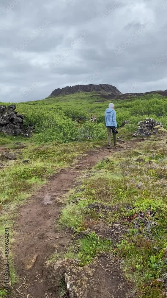 woman with a camera in her hands goes to Eldborg crater in Iceland woman with a camera in her hands goes to Eldborg crater in Iceland