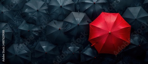 Standing out from the crowd, a red umbrella contrasts against a sea of black umbrellas for a striking visual effect.