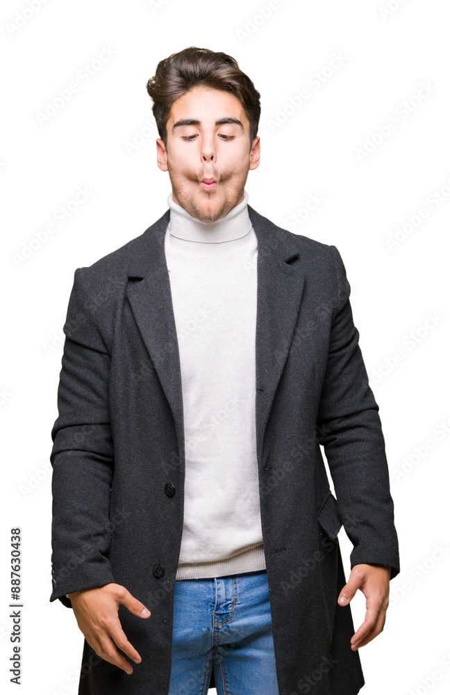 Young elegant man wearing winter coat over isolated background making fish face with lips, crazy and comical gesture. Funny expression.
