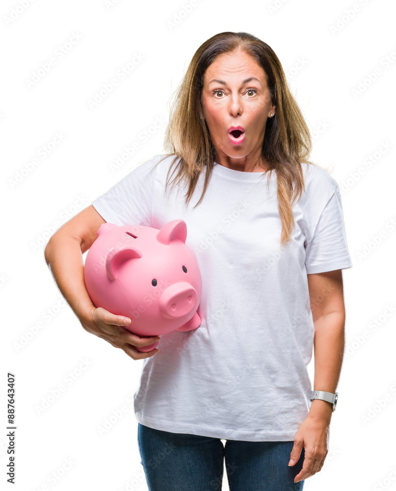 Middle age hispanic woman saving money using piggy bank over isolated background scared in shock with a surprise face, afraid and excited with fear expression Middle age hispanic woman saving money using piggy bank over isolated background scared in shock with a surprise face, afraid and excited with fear expression