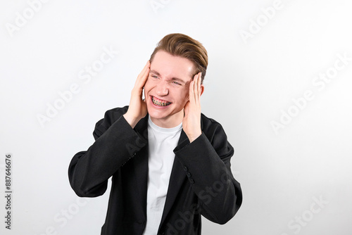 A middle-aged man standing outdoors, holding his hands to his ears as if protecting them from loud noise