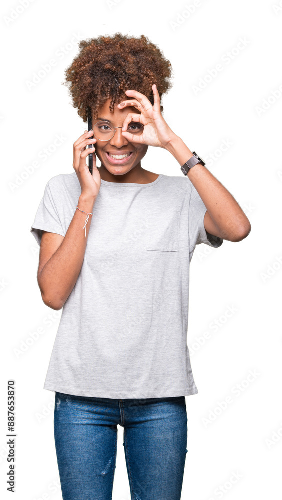 Young african american woman talking on smartphone over isolated background with happy face smiling doing ok sign with hand on eye looking through fingers Young african american woman talking on smartphone over isolated background with happy face smiling doing ok sign with hand on eye looking through fingers
