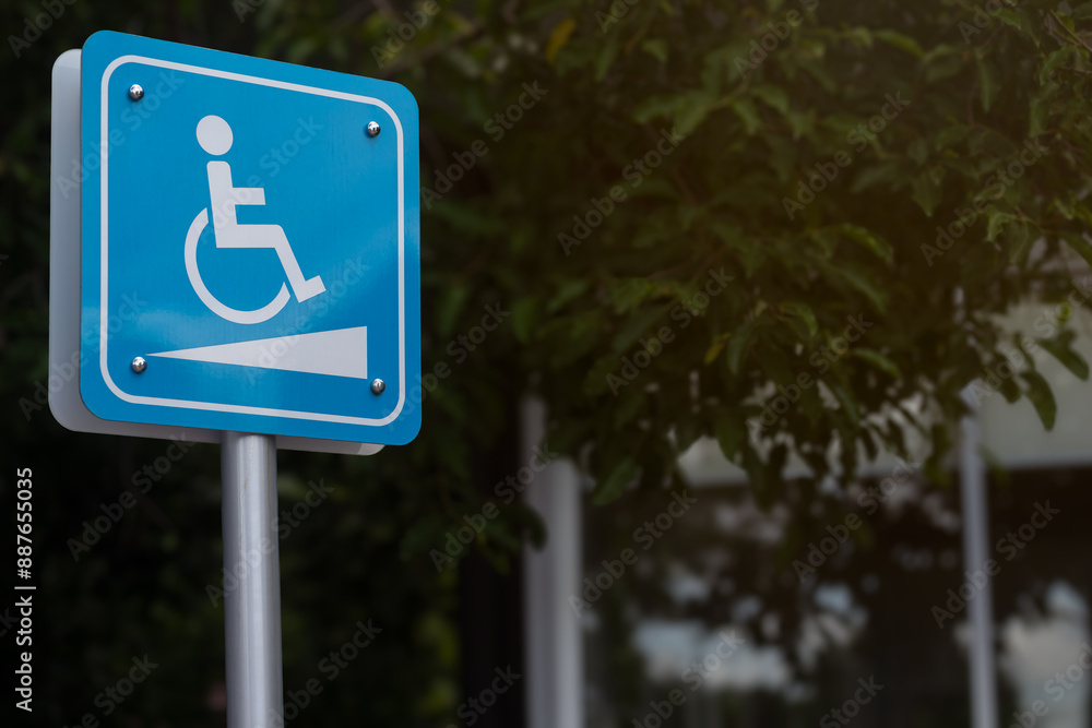 Disable person sign or wheelchair slope way symbol with blurred outdoors background. Disable person sign or wheelchair slope way symbol with blurred outdoors background.