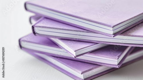 A stack of minimalist notebooks with solid purple covers, placed on a white surface