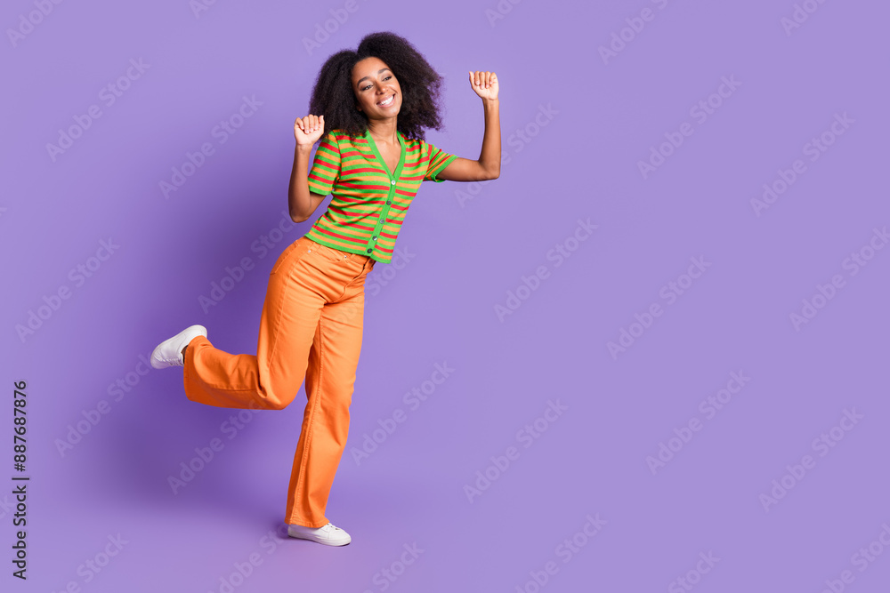 Full length photo of lucky positive woman wear striped shirt rising fists empty space isolated violet color background Full length photo of lucky positive woman wear striped shirt rising fists empty space isolated violet color background