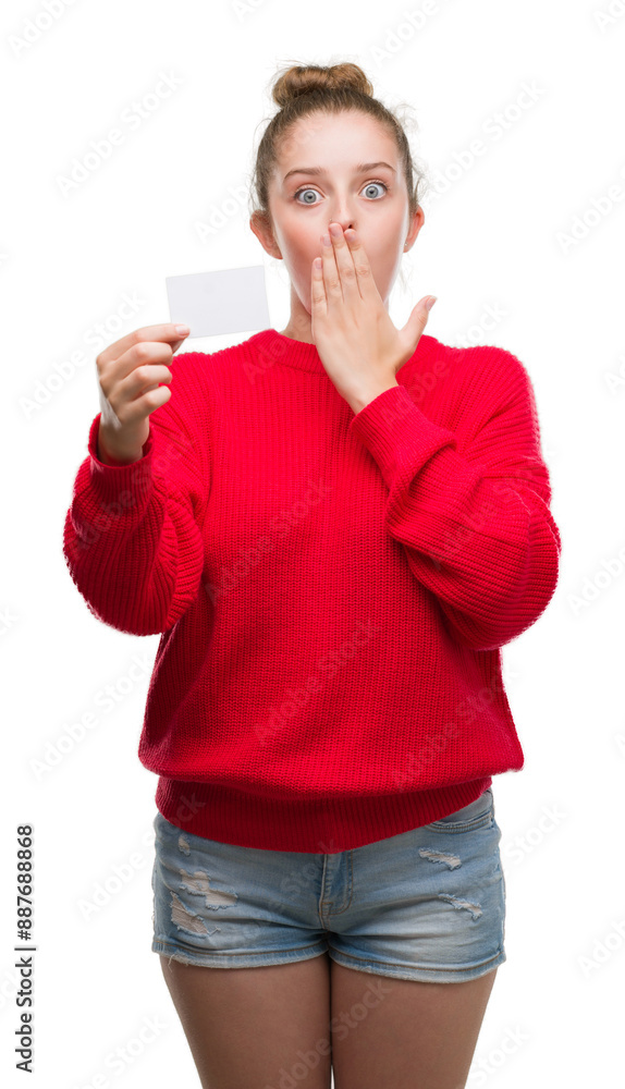 Young blonde woman holding advertising card cover mouth with hand shocked with shame for mistake, expression of fear, scared in silence, secret concept Young blonde woman holding advertising card cover mouth with hand shocked with shame for mistake, expression of fear, scared in silence, secret concept