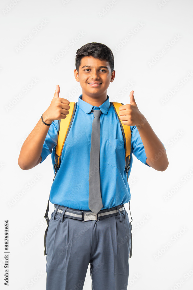 Indian Asian school boy in uniform with giving thumbs up, celebrating success or pointing to blank Indian Asian school boy in uniform with giving thumbs up, celebrating success or pointing to blank