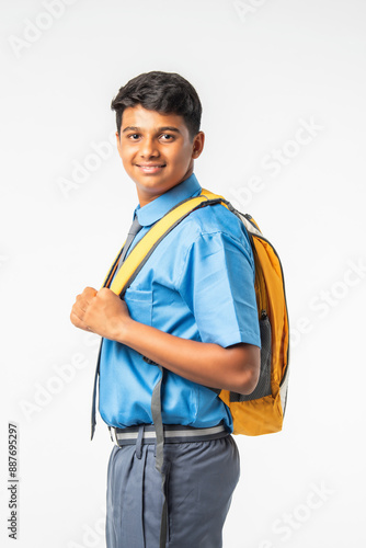 Indian Asian school boy in uniform with books or laptop and backpack, smiling and isolated © StockImageFactory