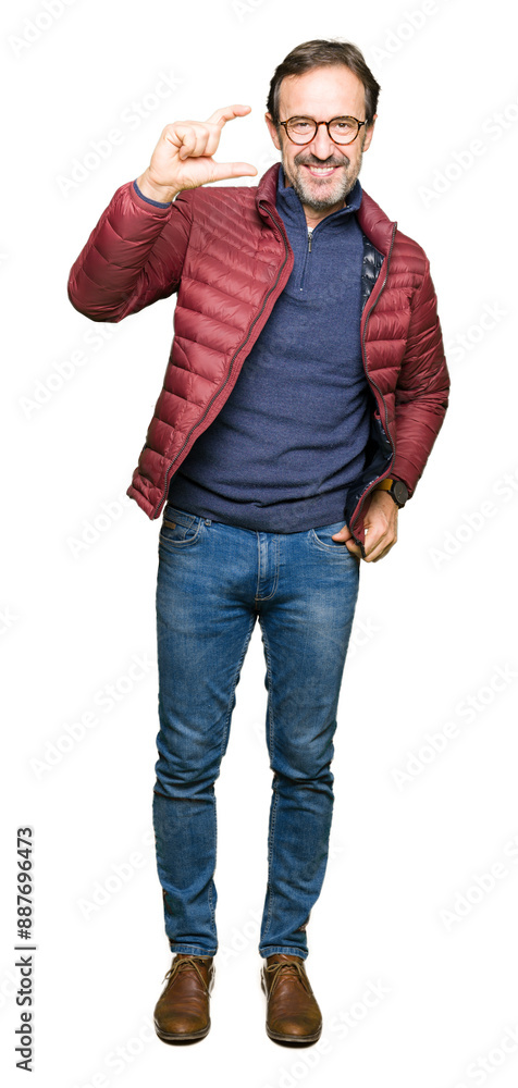 Middle age handsome man wearing glasses and winter coat smiling and confident gesturing with hand doing size sign with fingers while looking and the camera. Measure concept. Middle age handsome man wearing glasses and winter coat smiling and confident gesturing with hand doing size sign with fingers while looking and the camera. Measure concept.