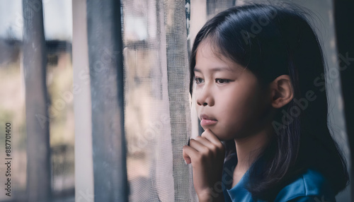 Staring sadly and gloomily out of the window. A feeling of being alone, depression, sadness. Asian girl. photo