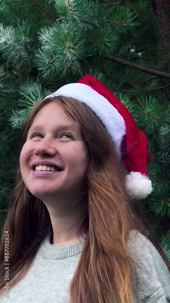 Happy young woman in Christmas hat is smiling, breathing deep fresh air outdoors in winter forest Happy young woman in Christmas hat is smiling, breathing deep fresh air outdoors in winter forest