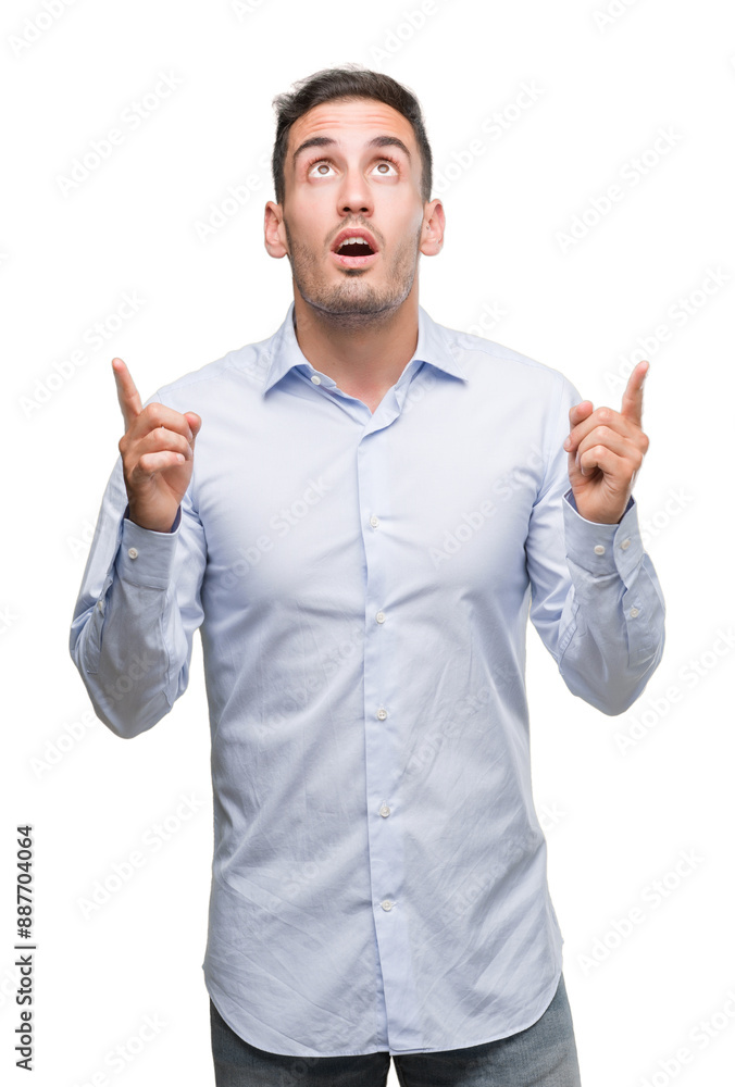 Handsome young businessman amazed and surprised looking up and pointing with fingers and raised arms. Handsome young businessman amazed and surprised looking up and pointing with fingers and raised arms.