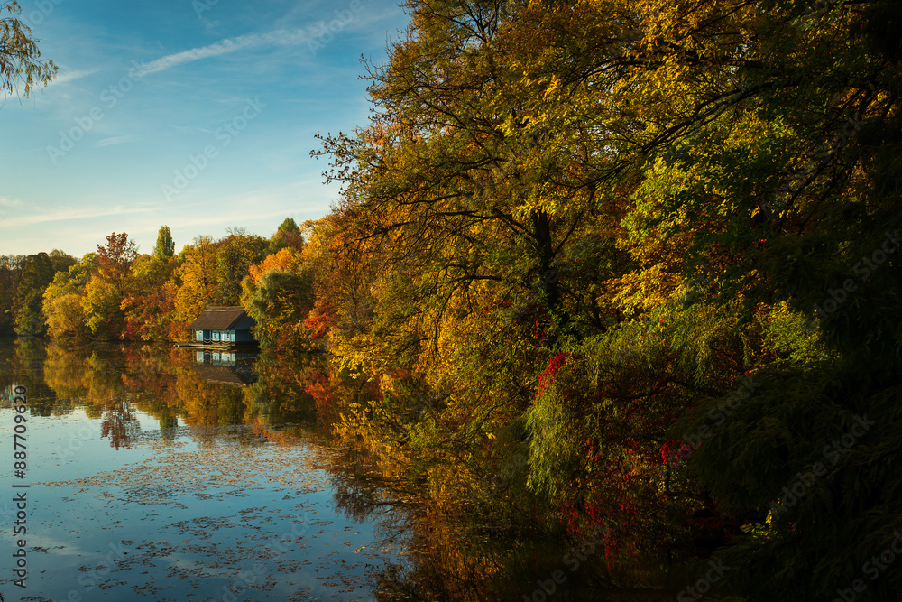 Landscape with beautiful house on a lake with colourful leafs in autumn season