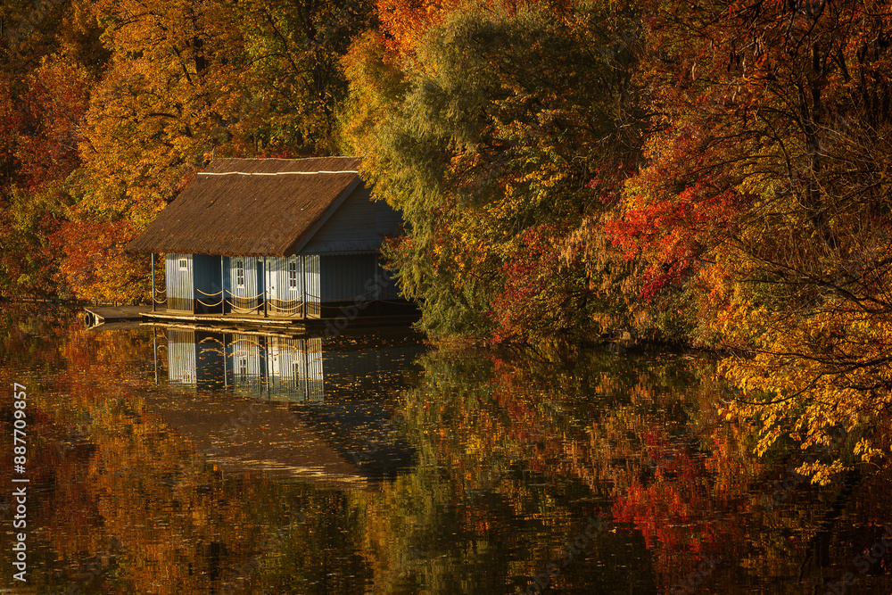 Landscape with beautiful house on a lake with colourful leafs in autumn season