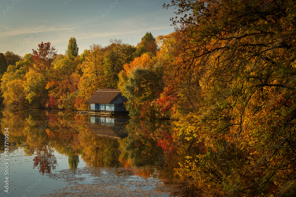 Landscape with beautiful house on a lake with colourful leafs in autumn season