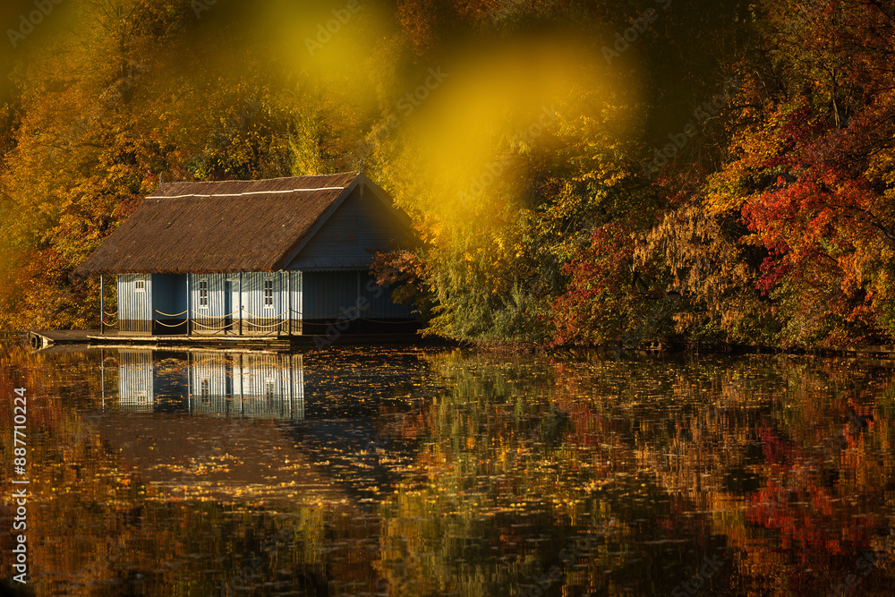 Landscape with beautiful house on a lake with colourful leafs in autumn season