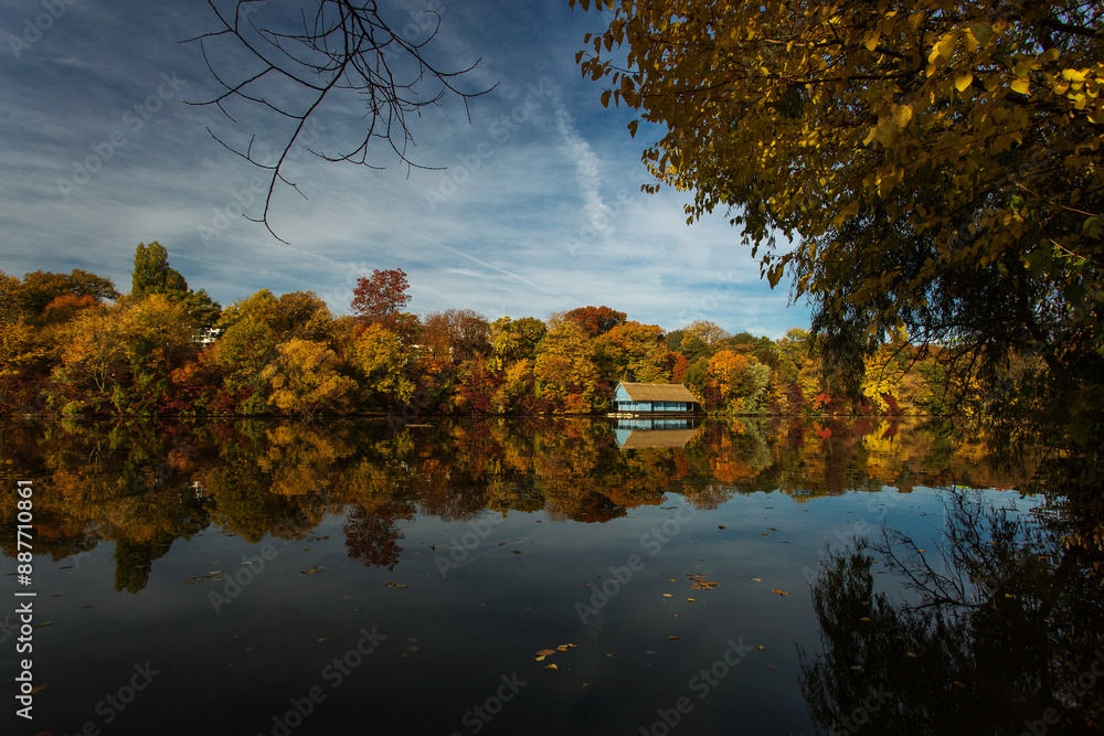 Landscape with beautiful house on a lake with colourful leafs in autumn season