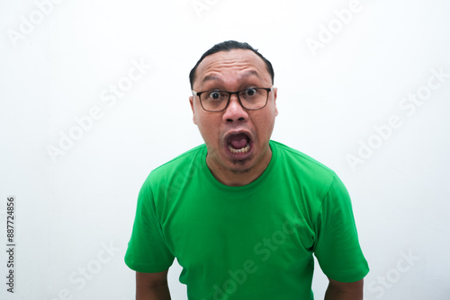 Vászonkép Shocked Asian man in green t-shirt, wide-eyed with surprised expression, humorou