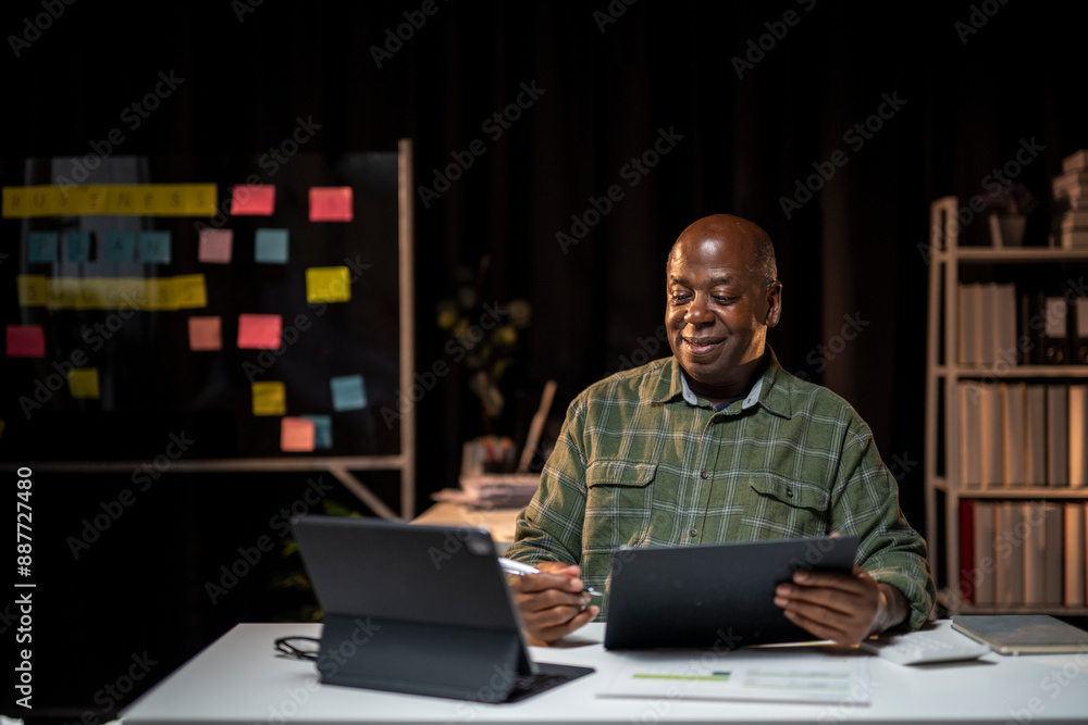 A man is sitting at a desk with a laptop and a stack of papers A man is sitting at a desk with a laptop and a stack of papers