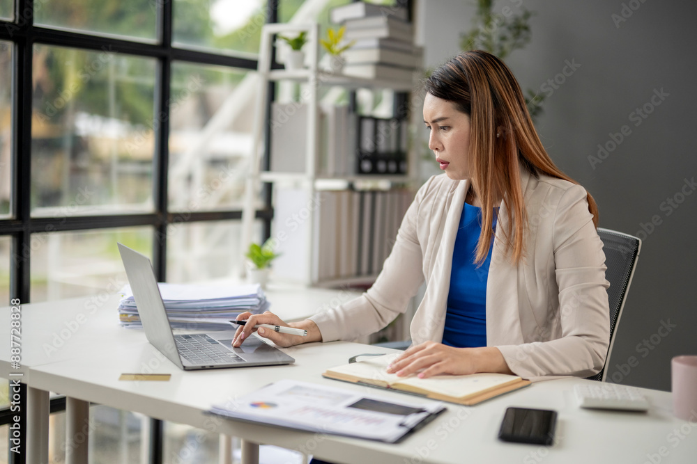 A woman is sitting at a desk with a laptop and a notebook A woman is sitting at a desk with a laptop and a notebook