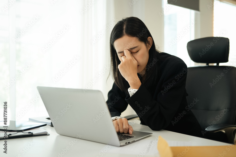Frustrated young businesswoman feeling eye pain while overworking on laptop at office Frustrated young businesswoman feeling eye pain while overworking on laptop at office