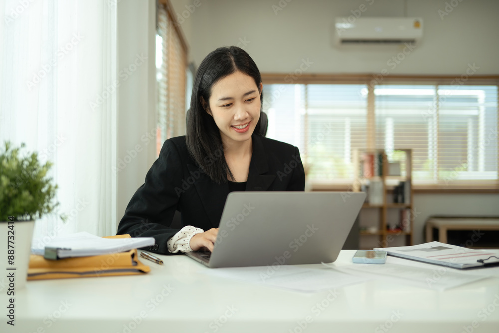 Charming asian businesswoman in black suit using laptop at home office Charming asian businesswoman in black suit using laptop at home office