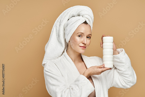 A woman in a robe showcases her natural beauty while holding a tube of cream.