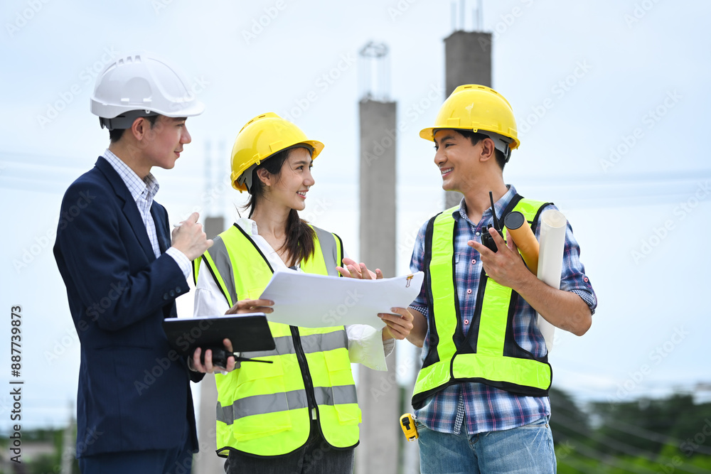 Engineers in safety helmet collaborating and sharing ideas, with construction pillars in the background Engineers in safety helmet collaborating and sharing ideas, with construction pillars in the background