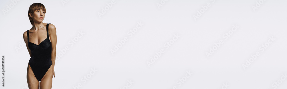 Fototapeta premium Stylish woman in black swimsuit posing on white backdrop.