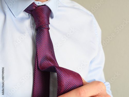 caucasian man in blue shirt with blue and red, purple tie. Professional and banker look. how to tie a perfect tie knot photo