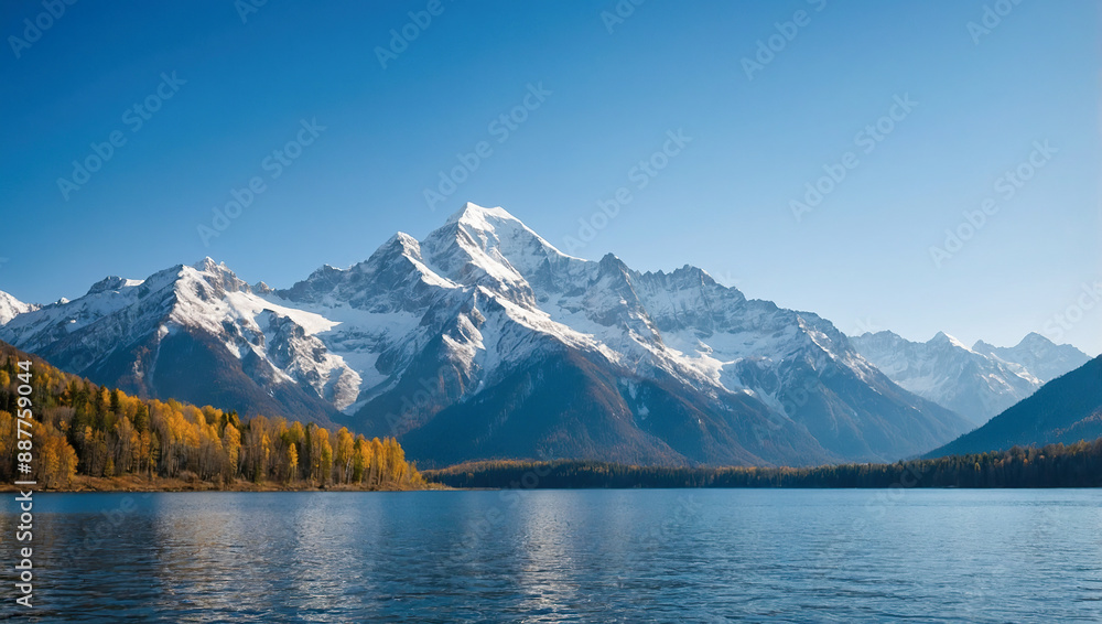 Naklejka premium Snowcapped mountains reflecting in a crystal-clear lake surrounded by forested hills under a bright blue sky.