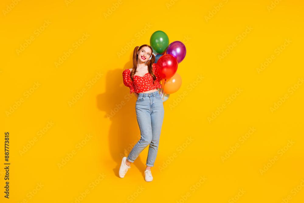 Full body photo of attractive young girl hold air balloons look empty space dressed stylish red clothes isolated on yellow color background Full body photo of attractive young girl hold air balloons look empty space dressed stylish red clothes isolated on yellow color background