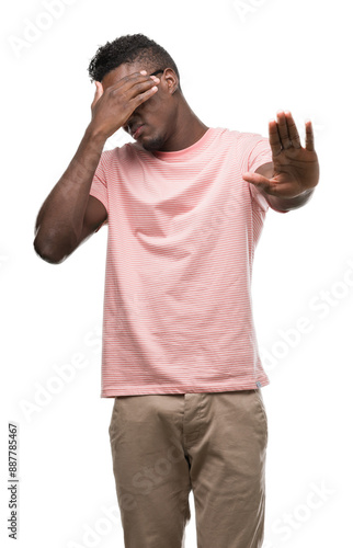 Young african american man wearing pink t-shirt covering eyes with hands and doing stop gesture with sad and fear expression. Embarrassed and negative concept.