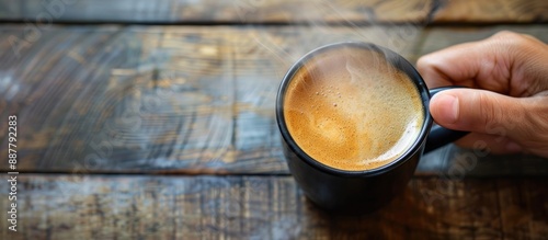A hand with a black cup of ...
