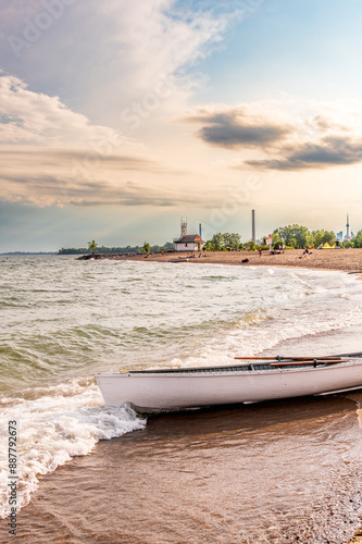Photography Beach day:  white rowboat on the sand of a public beach with people in backgroun