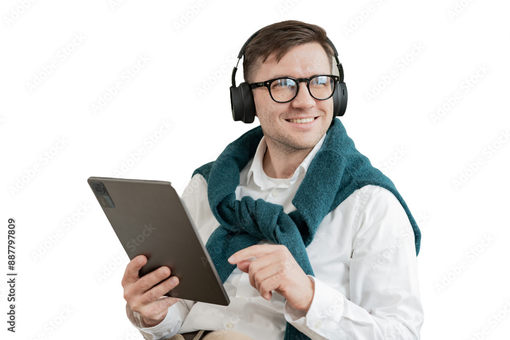 A male freelancer uses a tablet and headphones, listens to a player list in an application with music. Cut out A male freelancer uses a tablet and headphones, listens to a player list in an application with music. Cut out