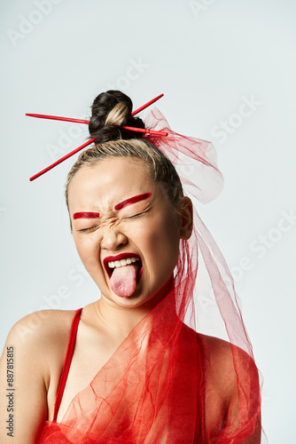 A vibrant Asian woman in a red dress cheekily sticks out her tongue. photo