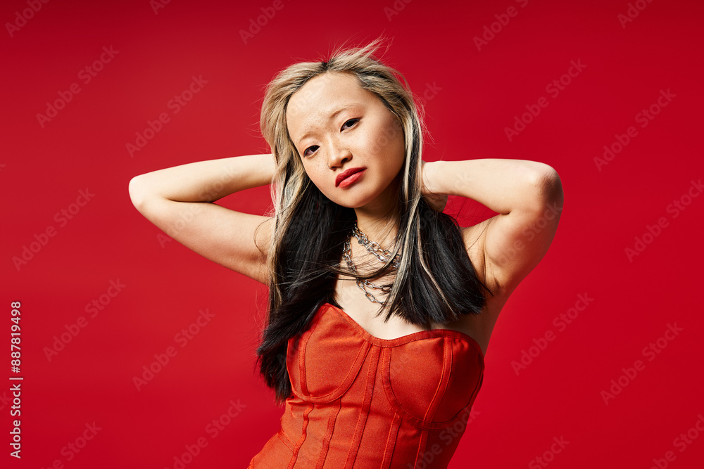 Asian woman in striking red dress posing gracefully. Asian woman in striking red dress posing gracefully.