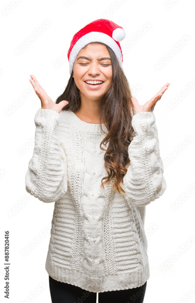 Young arab woman wearing christmas hat over isolated background celebrating mad and crazy for success with arms raised and closed eyes screaming excited. Winner concept Young arab woman wearing christmas hat over isolated background celebrating mad and crazy for success with arms raised and closed eyes screaming excited. Winner concept